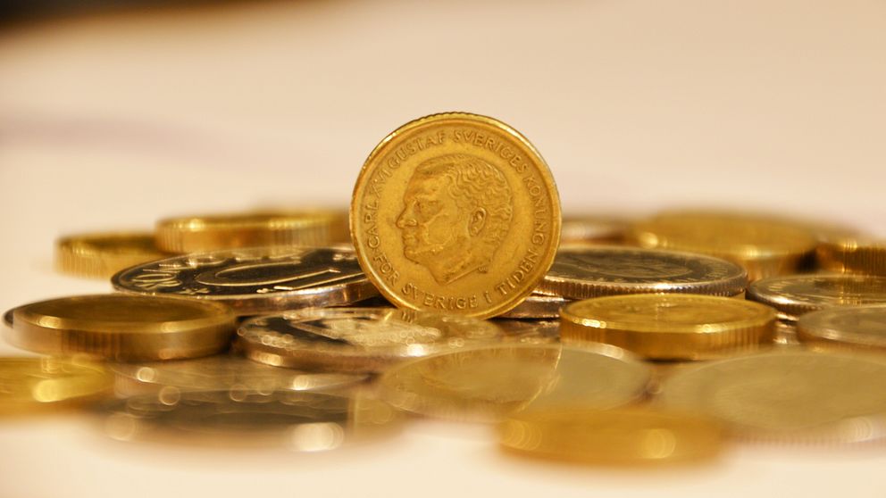 Tiokrona stående på högkant på en hög av mynt.