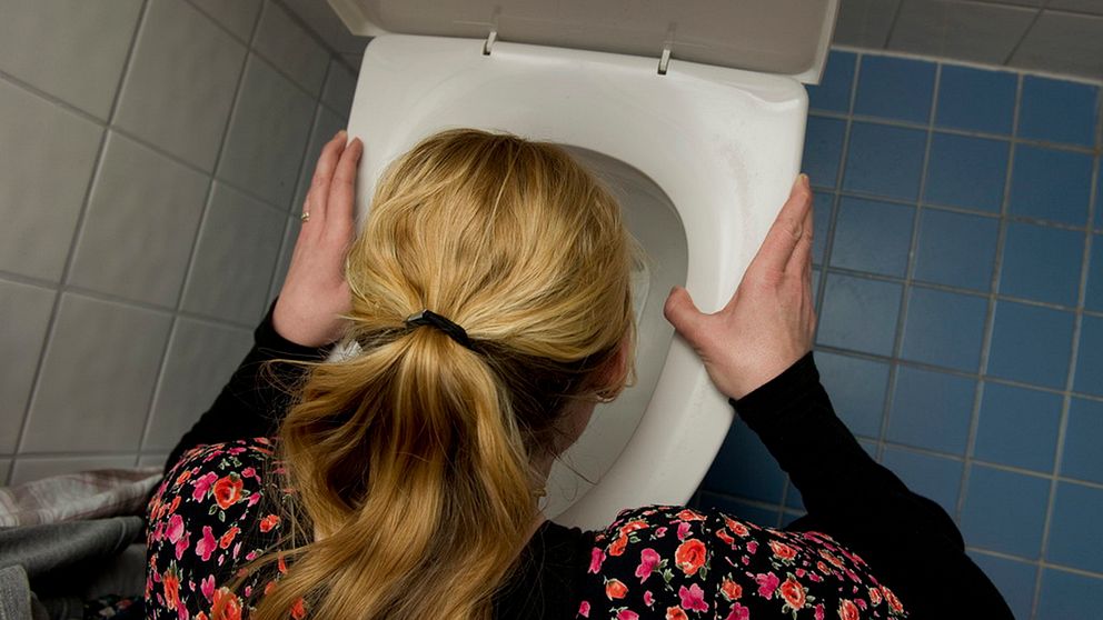 Kvinna hukar över toalett.