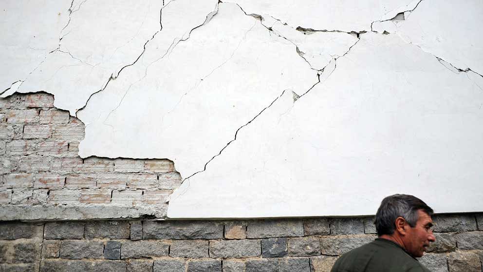 En man framför sitt förstörda hus i byn Rudarci utanför Pernik. AFP PHOTO / NIKOLAY DOYCHINOV