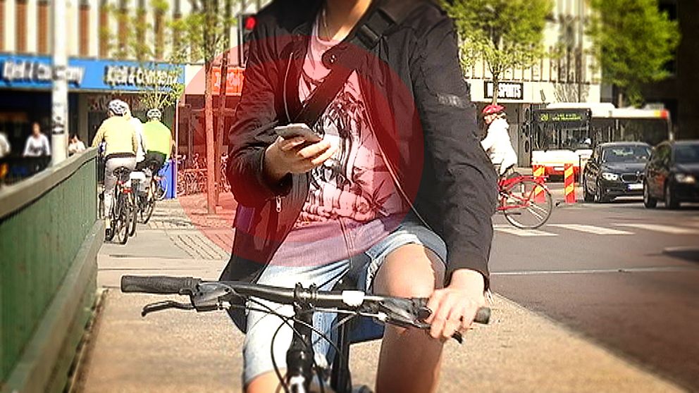 Cyklist tittar på mobilen medan han cyklar.