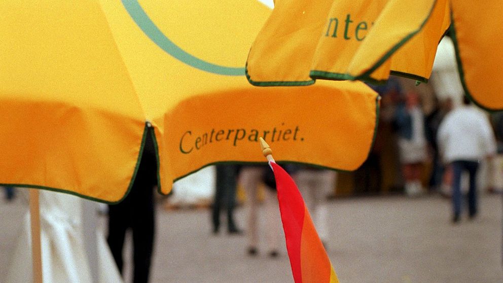 Centerpartiets logotyp på parasoll och en pride-flagga