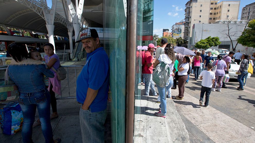 Människor utanför en stängd shoppinggalleria i Caracas.
