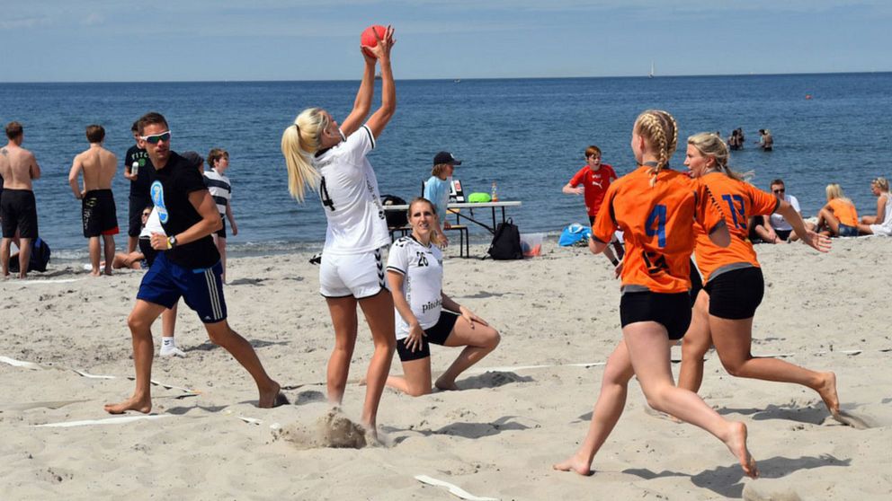 På bilden syns ungdomar spela beach handboll på en strand i Åhus.