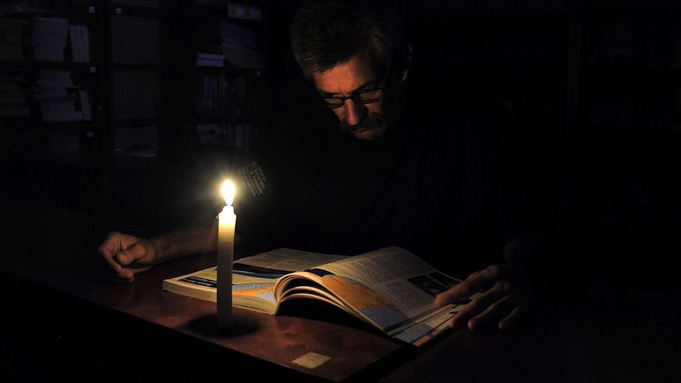 En man läser i skenet av stearinljus under ett av många elavbrott i Venezuela.