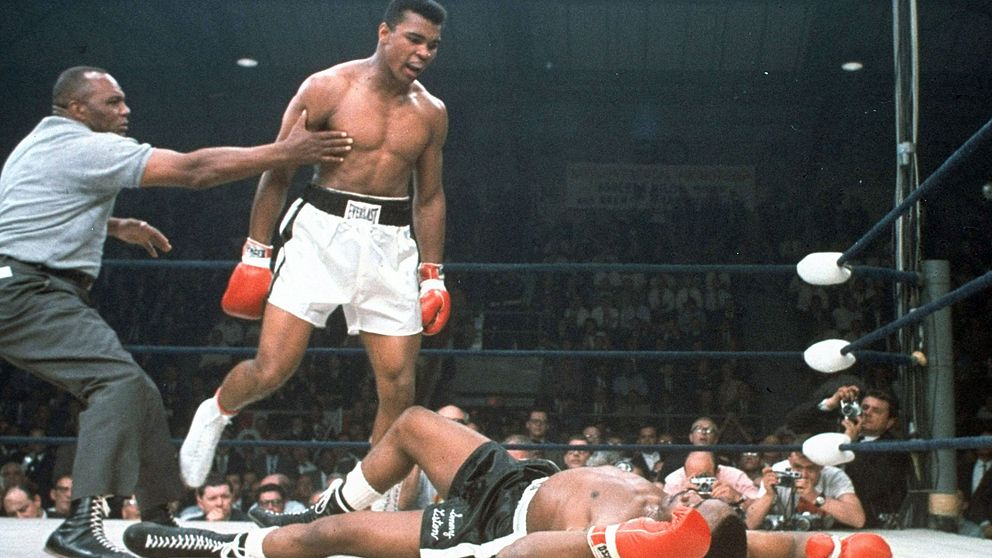 Mohammad Ali hålls tillbaka av domaren Joe Walcott efter att han knockat motståndaren Sonny Liston i första ronden under en match i Lewiston, Maine 1965.