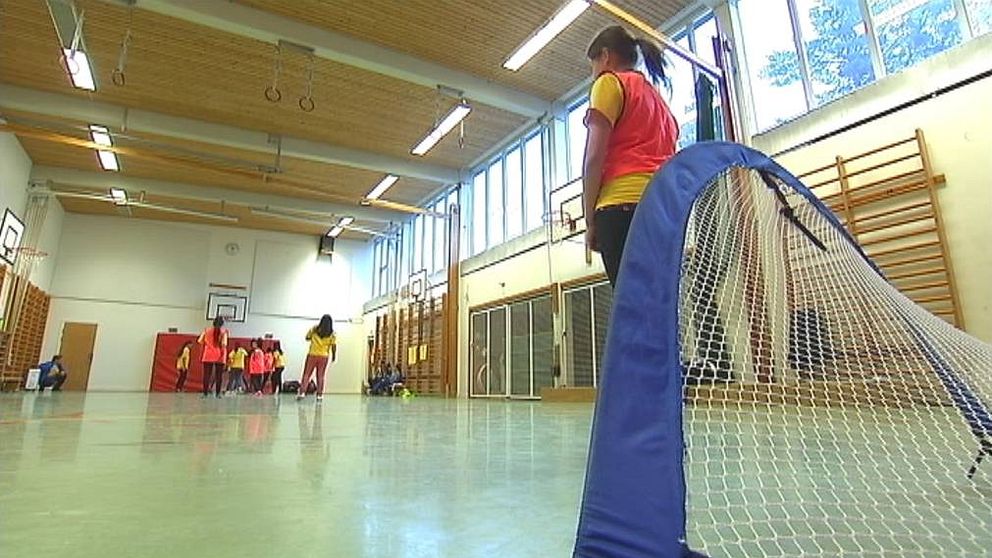 Skolidrottshall med barn som spelar innefotboll.