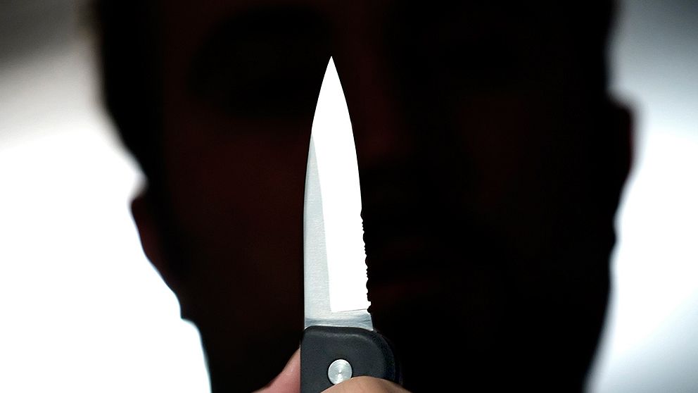 genrebild av manligshiluett som håller upp en kniv.
