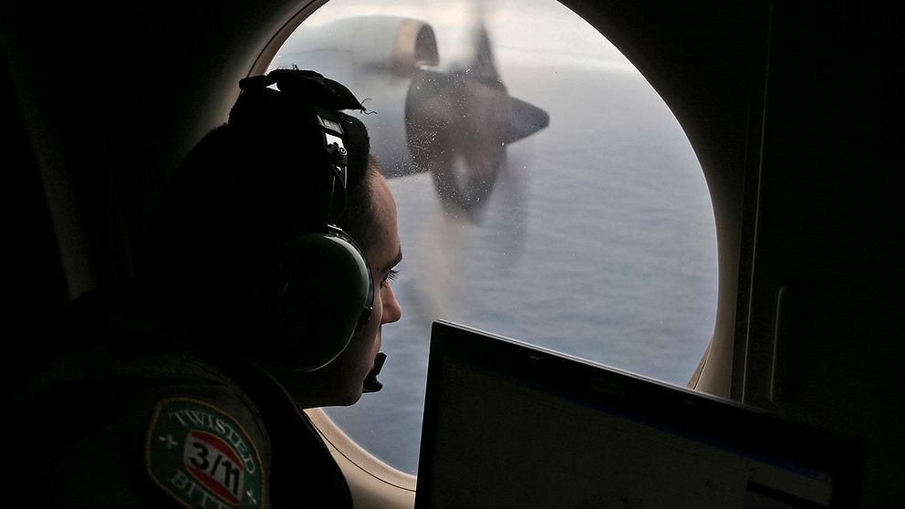 En man spanar efter flight MH370 genom ett flygplansfönster.