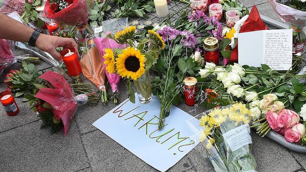 Blommor och en skylt med texten: ”Varför?” i närheten av shoppingcentret i München där skottdramat ägde rum på fredagen.
