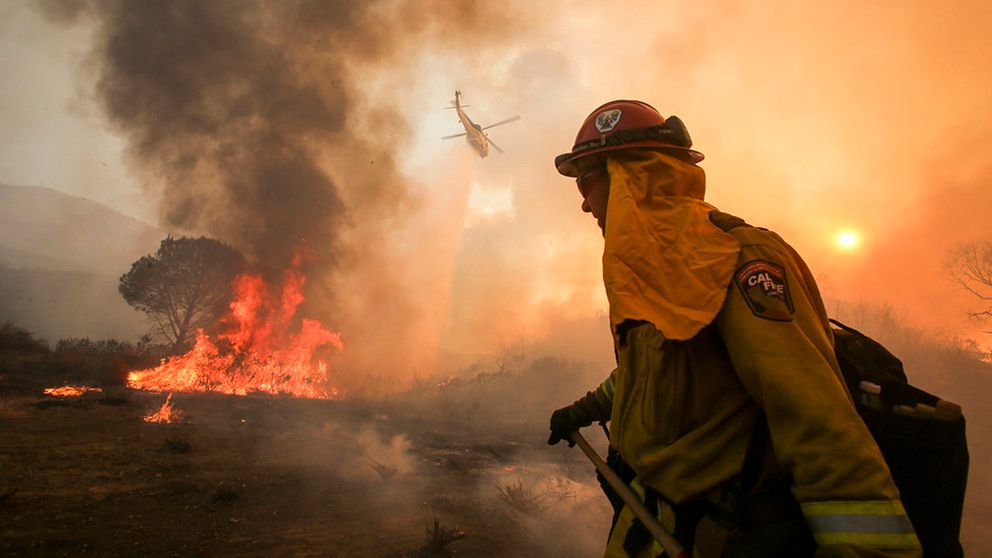 En brandman arbetar för att få bukt med den stora branden i Santa Clarita i Kalifornien.