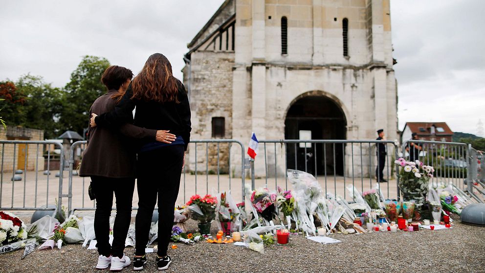 Två personer sörjer vid kyrkan.