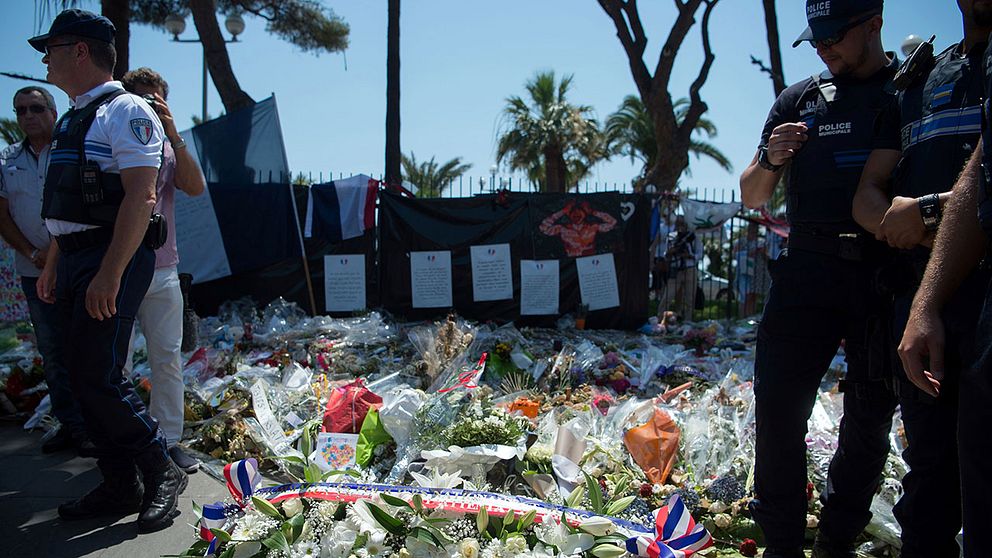 Polis framför nedlagda blommor i Nice.
