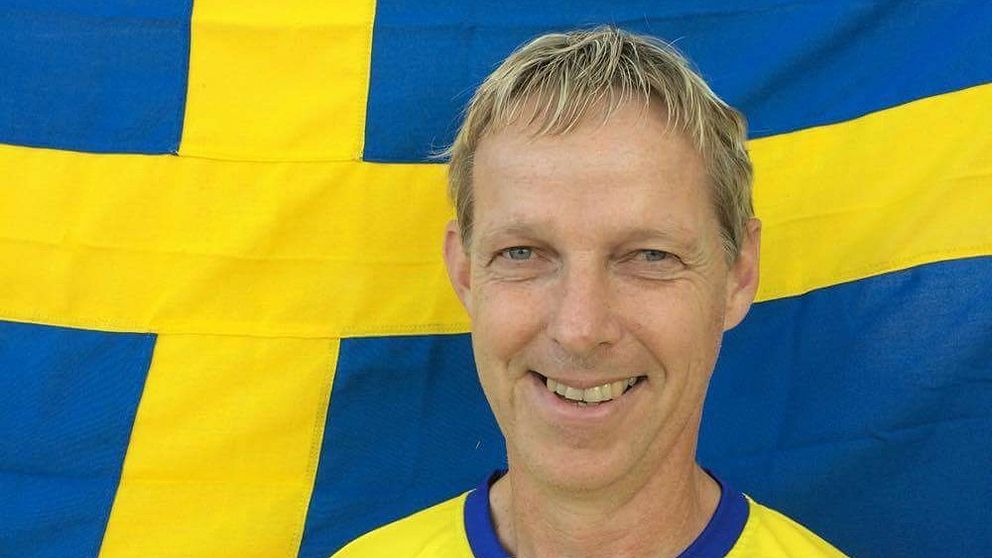 Olof Olsson står framför svenska flaggan.
