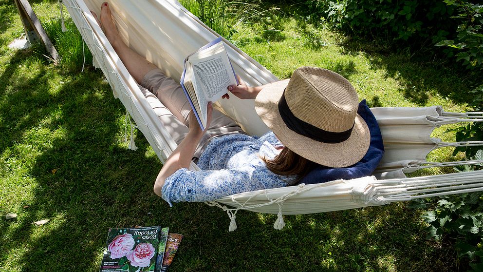 Kvinna läser i en hängmatta.