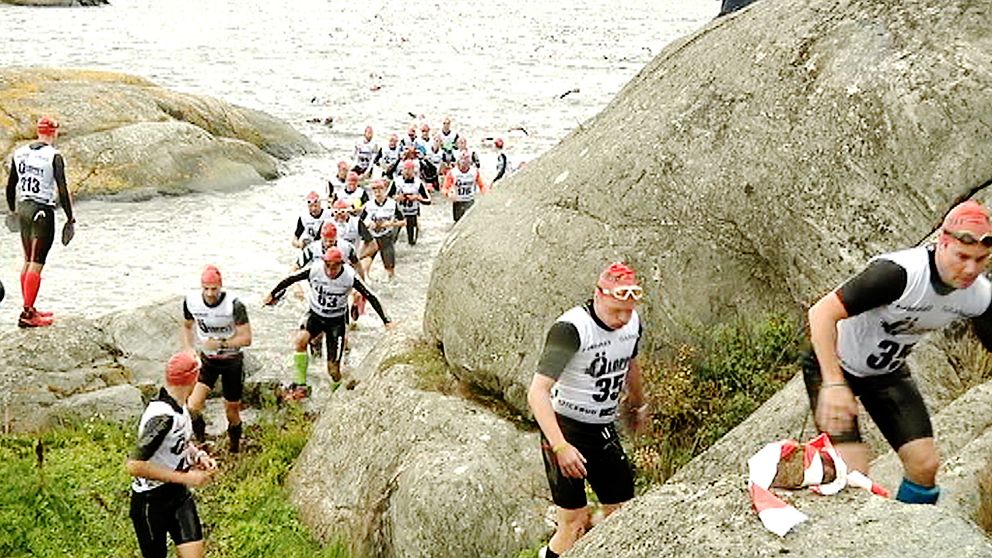 Deltagarna tar sig upp ur havet och springer på klippor.