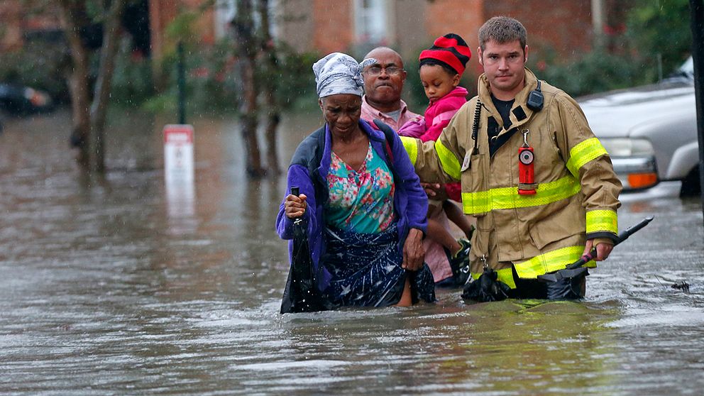 Brandkåren hjälper människor som vadar genom vatten i Baton Rouge.