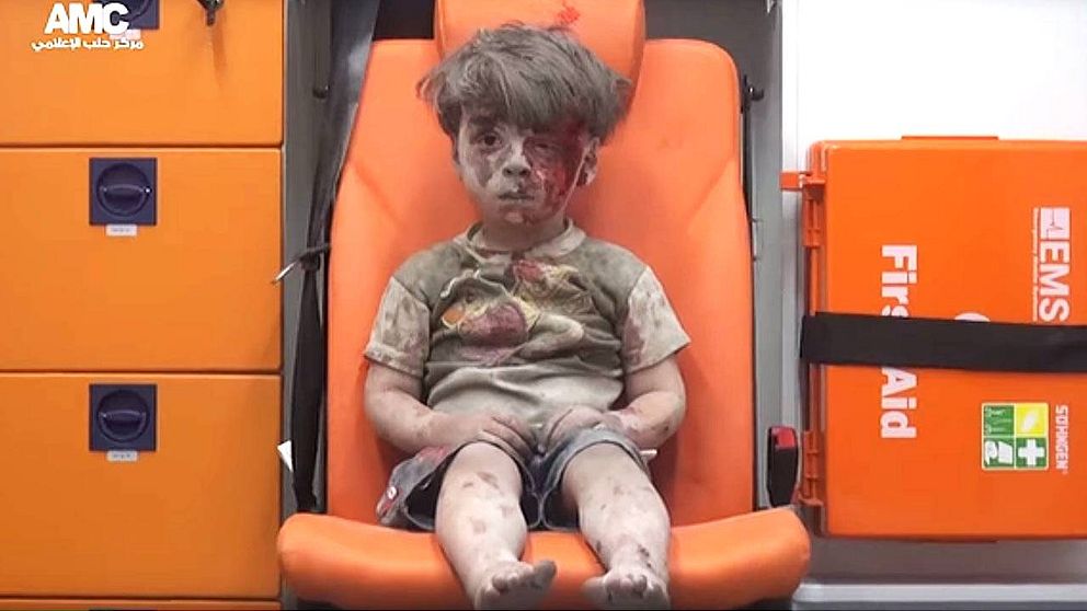 Omran, 5, täckt av byggdam och blod, i ambulansen.