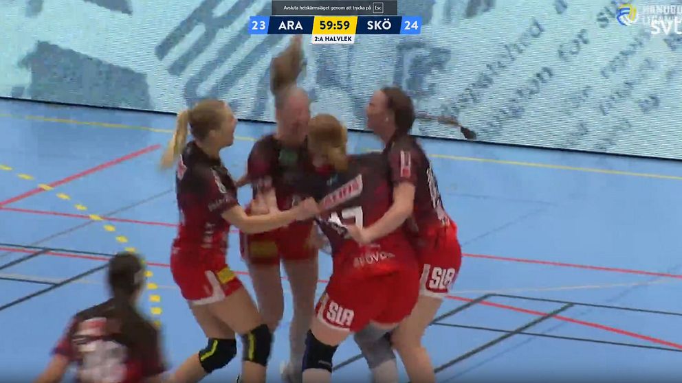 Fyra handbollsspelare i röd-svarta matchdräkter firar tillsammans på planen under en match. Spelare från laget Skövde vinner över Aranäs med ställningen 24-23, medan matchens klocka visar 59:59.