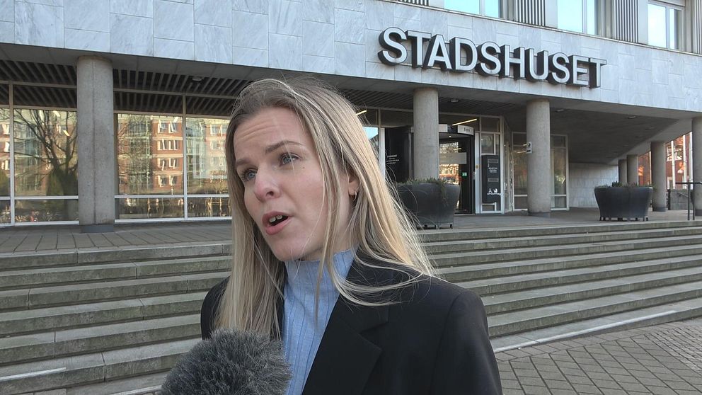 Person framför stadshuset intervjuas av media utanför byggnaden.