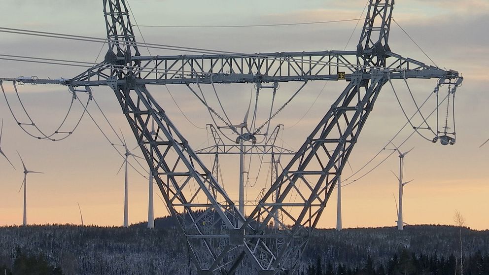 kraftledningsstolpe med vindkraftsverk i bakgrunden