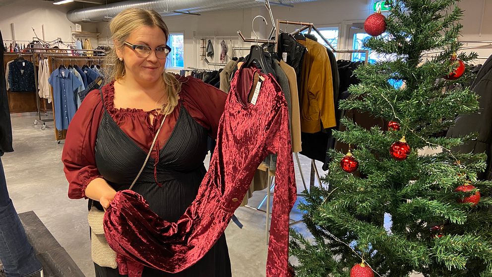 Kvinna håller upp en röd klänning i en butik.