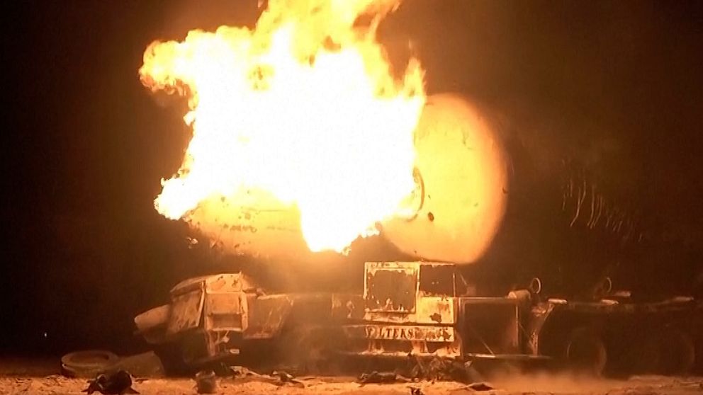 Militärfordon i fullt brandförlopp under natten.