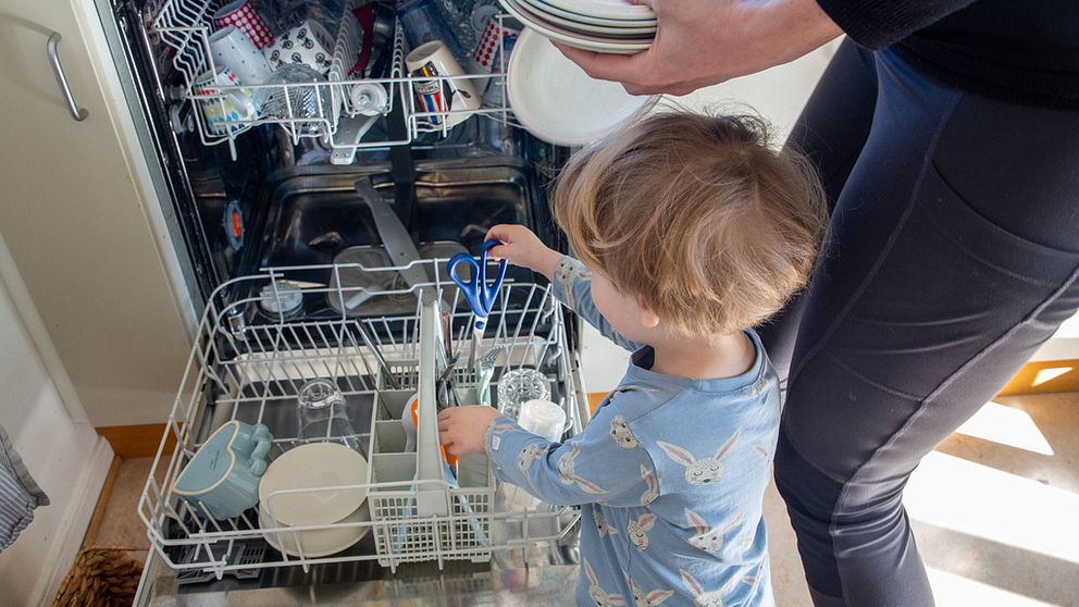 Förälder och barn hjälps åt att plocka ur diskmaskin.