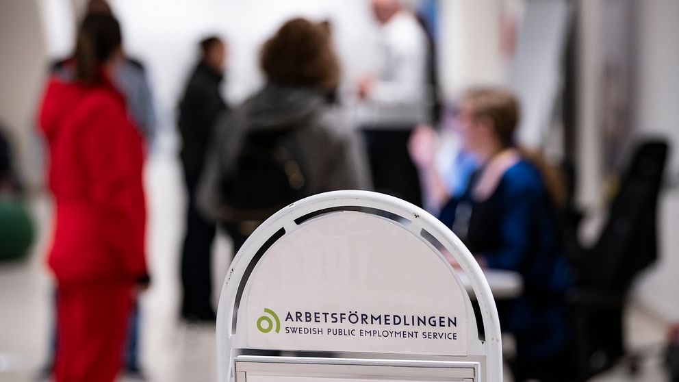 En Arbetsförmedlingen-skylt och personer i bakgrunden