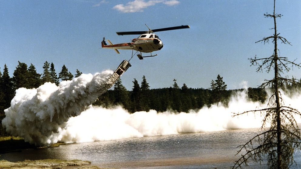 Helikopter på låg höjd fäller kalk över sjö.