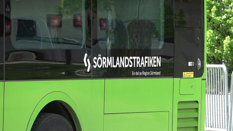 En grön buss från Sörmlandstrafiken, med texten ”En del av Region Sörmland” på sidan, parkerad utomhus.