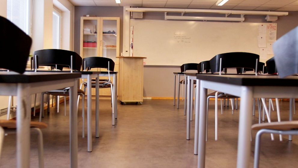 Tomt klassrum med stolar och bord riktade mot en vit tavla.