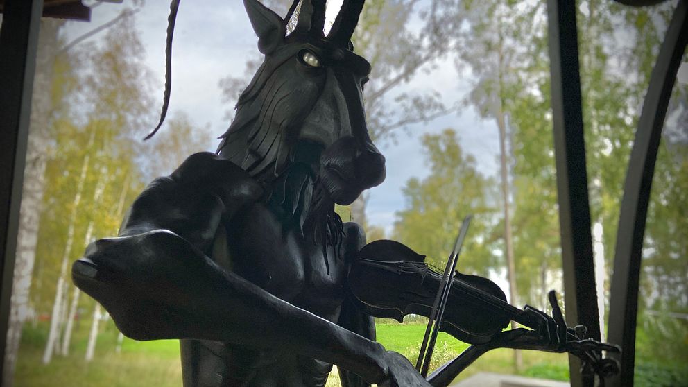 En järnstaty föreställande en bock som står på bakbenen och spelar fiol.
