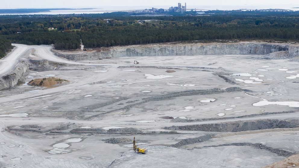 Kalkbrottet i Slite med grävmaskin, skog i bakgrunden och Slite i horisonten.