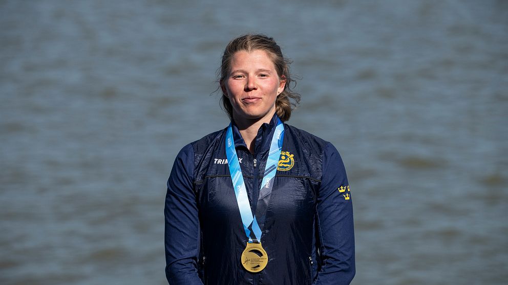 Kanotisten Melina Andersson står framför vatten med en medalj runt halsen .