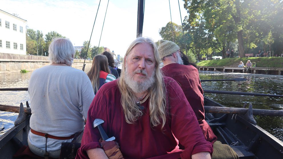Arkeologen Anders Ekberg tittar in i kameran sittandes på vikingabåten Sefnir.