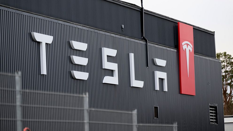 Fasad av en Tesla-byggnad med företagets logotyp och namn synligt.