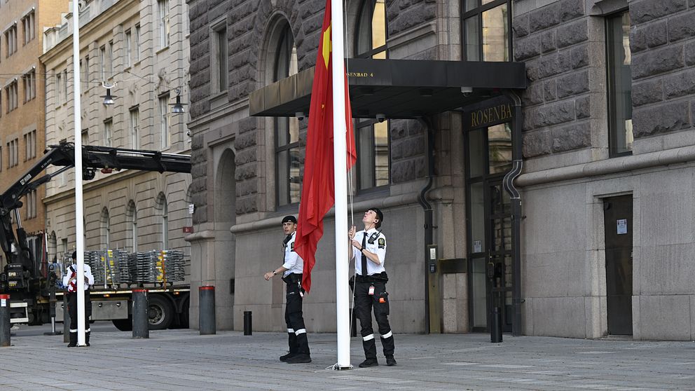 Poliser hissar amerikanska flaggan inför handelssamtal i Stockholm.
