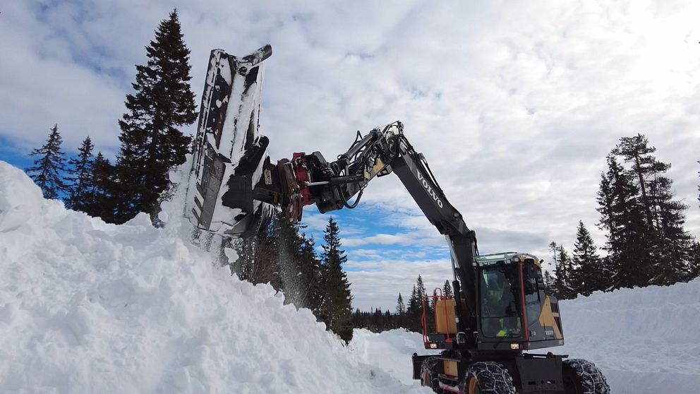 Grävmaskin med plog skyfflar undan snömassor i Sälenfjällen