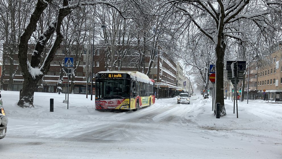 En snötäckt gata med en buss som står stilla med texten ej i trafik.