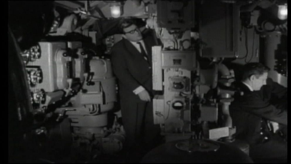 En man i kostym går runt i en ubåt.