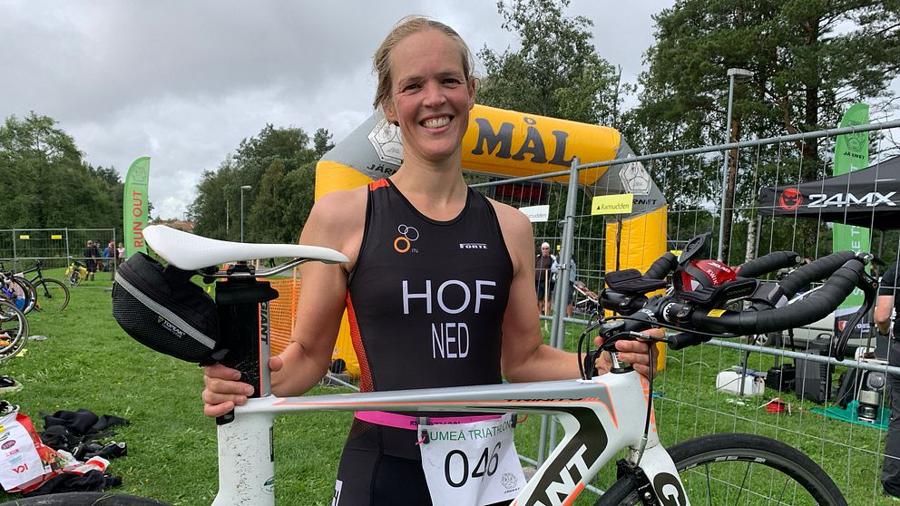 en kvinnlig idrottare håller upp en landsvägcykel framför en målportal