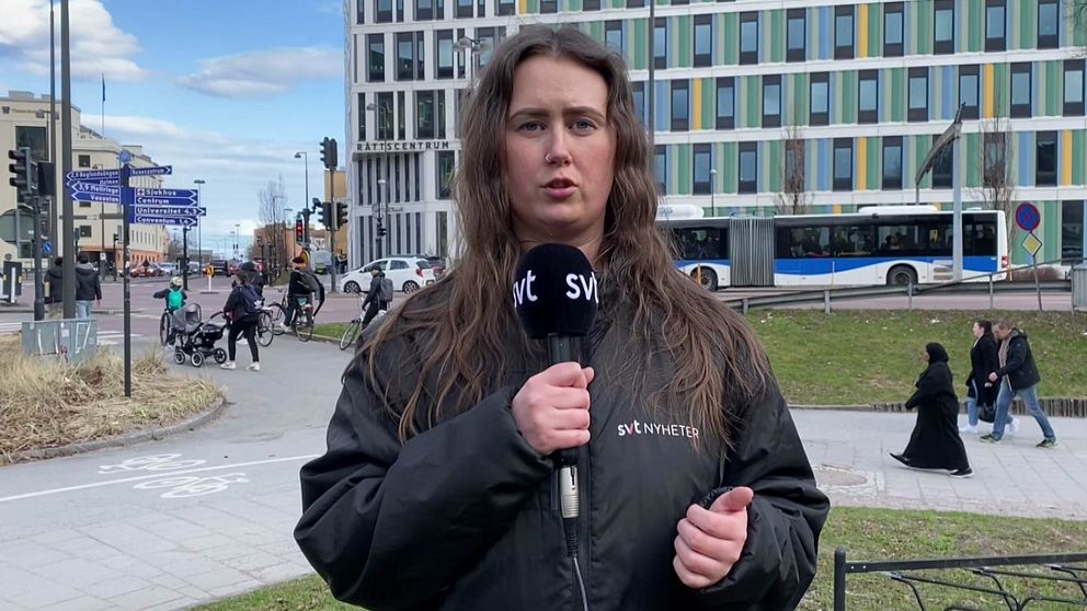 På bilden syns SVT:s reporter Hannah Gustafsson som pratar. Hon står framför tingshuset i Örebro. Bakom henne går och cyklar männsikor.