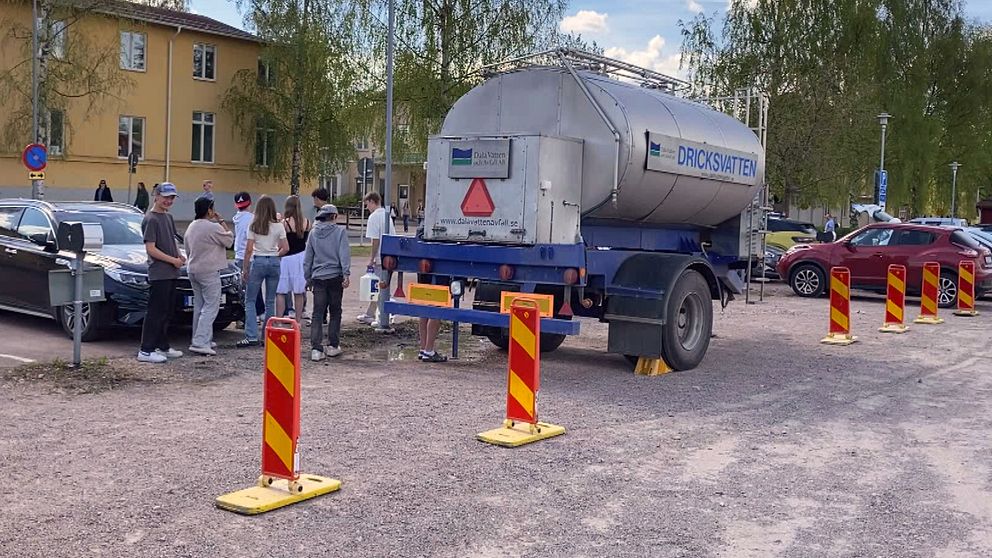 en vattentank och flera personer som står runt omkring.