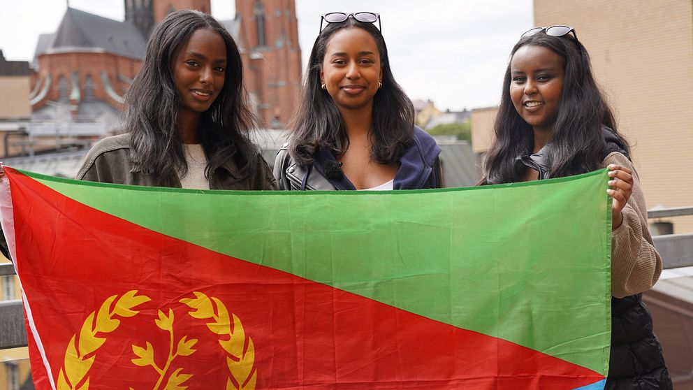 Tre unga tjejer håller Eritreas flagga