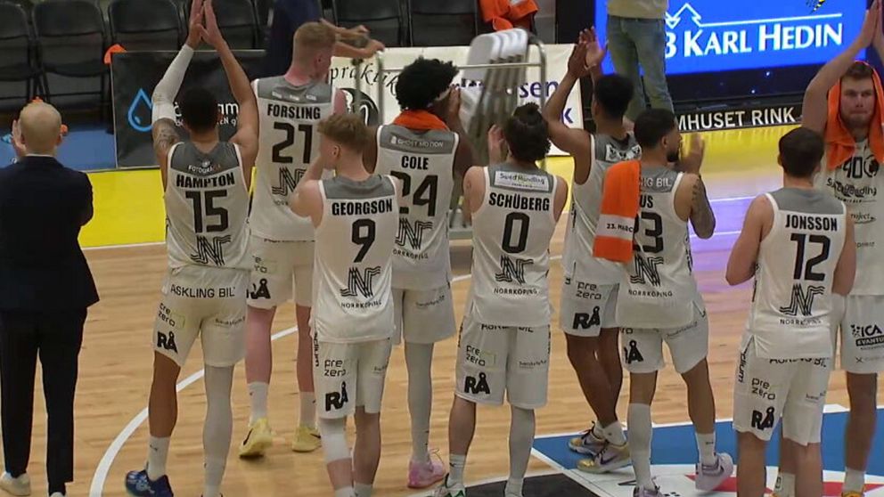 Basketlag klappar och tackar publiken efter match på inomhusplan.