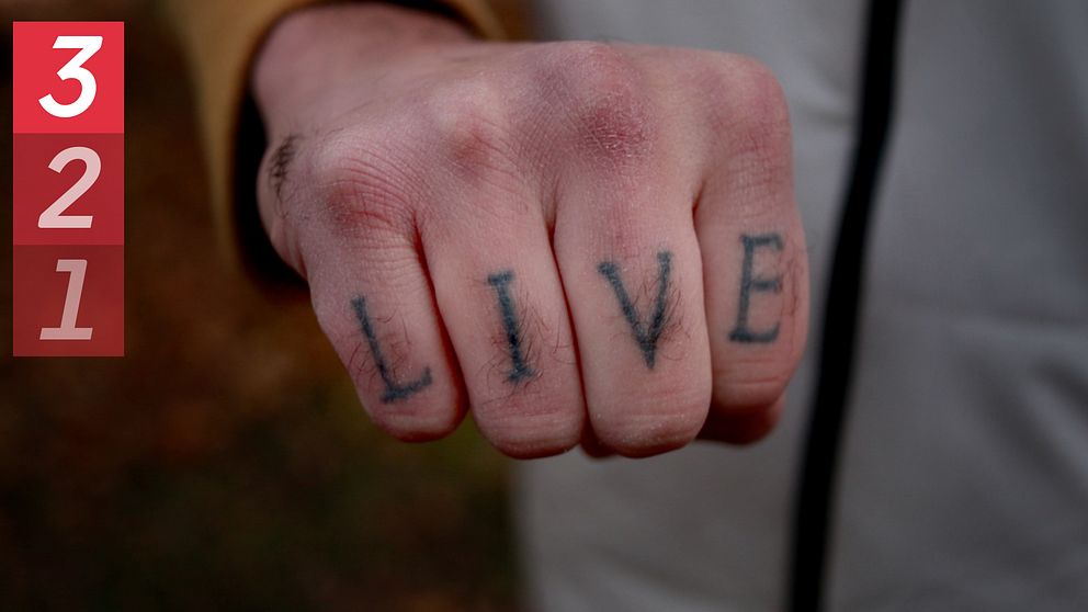 Hand med tatuering där det står ”live”