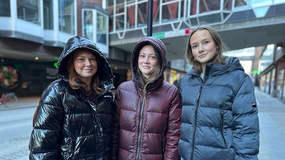 Tre tjejer i 18-årsåldern, två med svarta jackor och en i vinröd, inne i centrala Västerås.