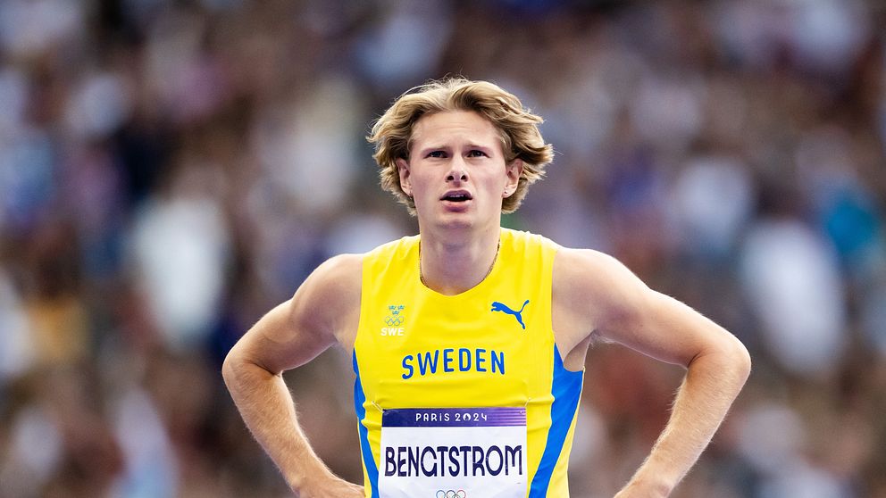 Svensk atlet i gult och blått sportställ med namnet ”BENGTSTRÖM” synlig på bröstet, står med en fokus på tävlingen bakom honom. Grottade människor och en arena kan skymtas i bakgrunden.