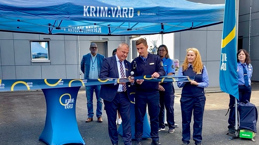 Två män klipper band. Blått tält med text Krim:vård i bakgrunden