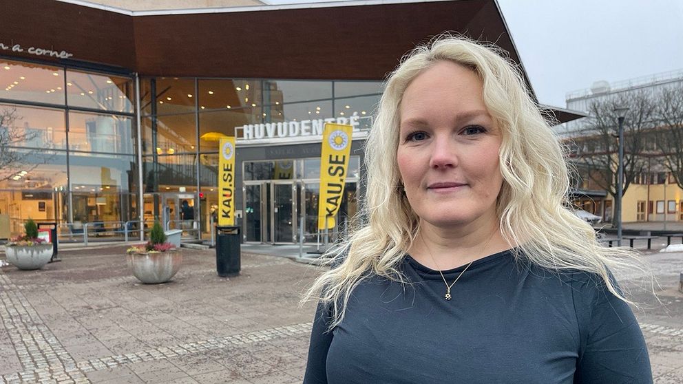 Anna Sjöberg står framför Karlstads universitet, Omgivningen är grå och regnig, med några planteringar och stenar på marken.